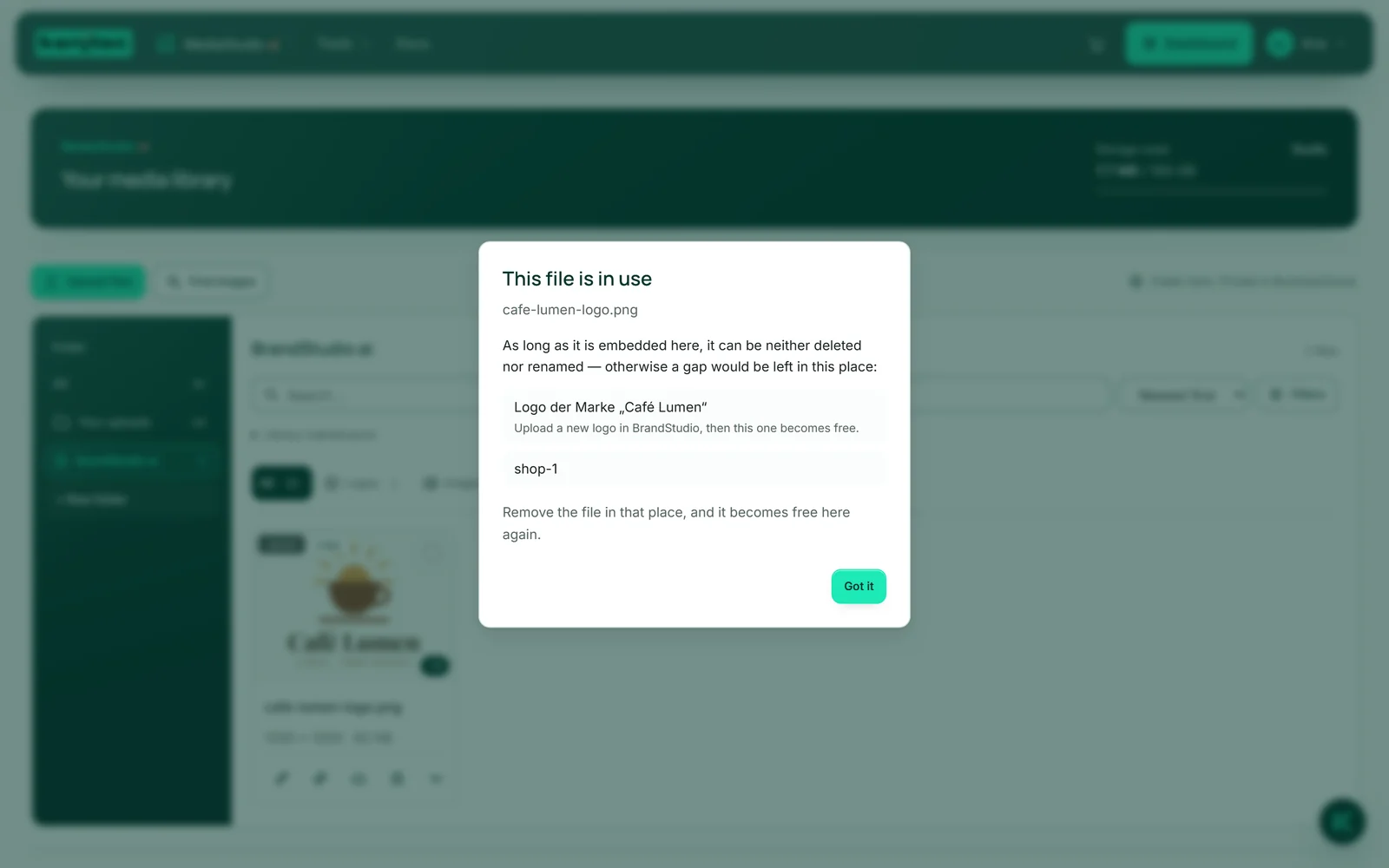 في المجلد «BrandStudio ai» نافذة الحوار «هذا الملف قيد الاستخدام» لشعار Café Lumen: شعار العلامة التجارية بوصفه موضع الاستخدام، وأسفله الجملة التي تفيد بأن رفع شعار جديد في BrandStudio يحرّر الشعار القديم.